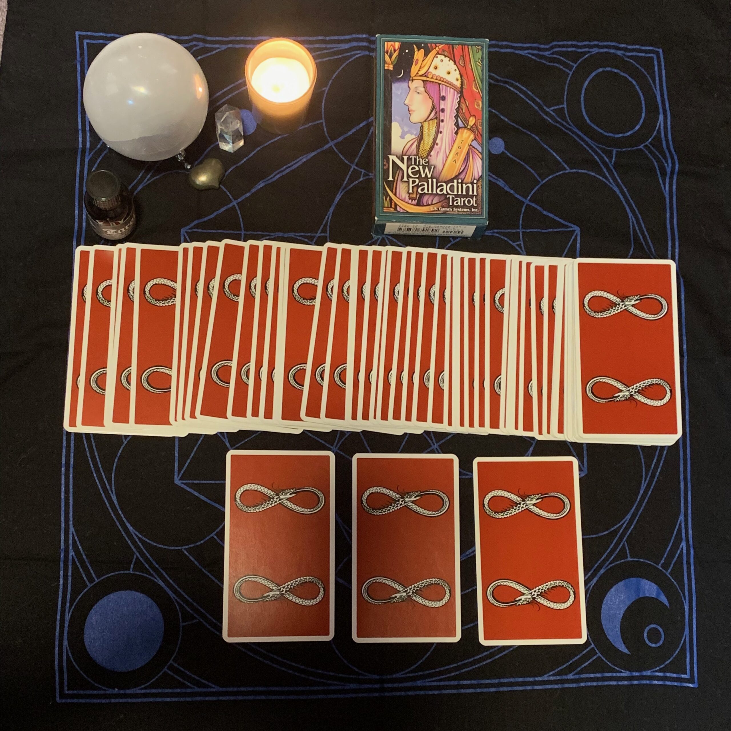 tarot reading scene. card backs of The New Palladini Tarot featuring a snake eating it's tail in the shape of the infinity symbol